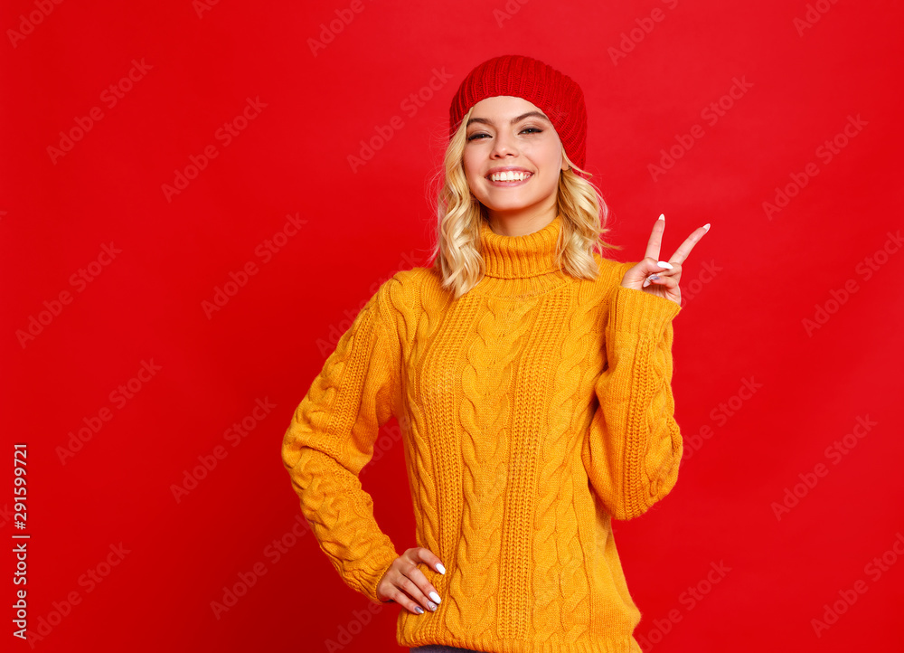 快乐、感性、开朗的女孩，带着红色背景的针织秋帽大笑。