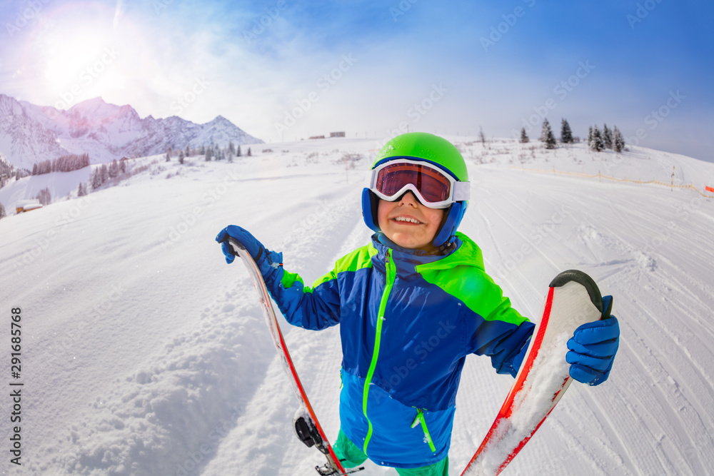 滑雪坡上的快乐男孩抱着滑雪仰视微笑