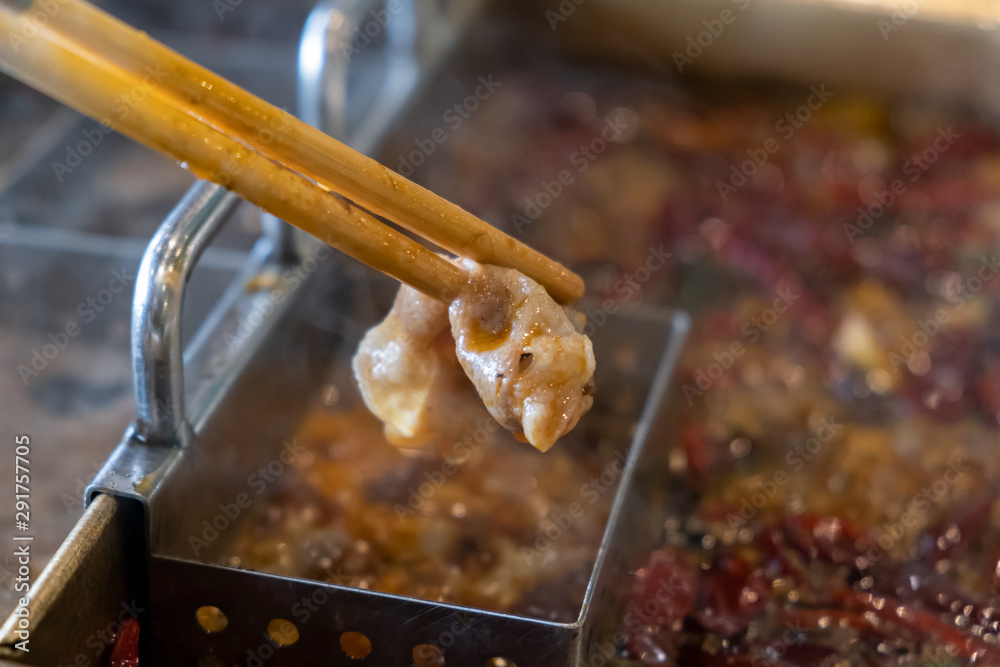 用筷子切牛肉，在热辣的红辣椒汤中煮，称为涮锅麻辣