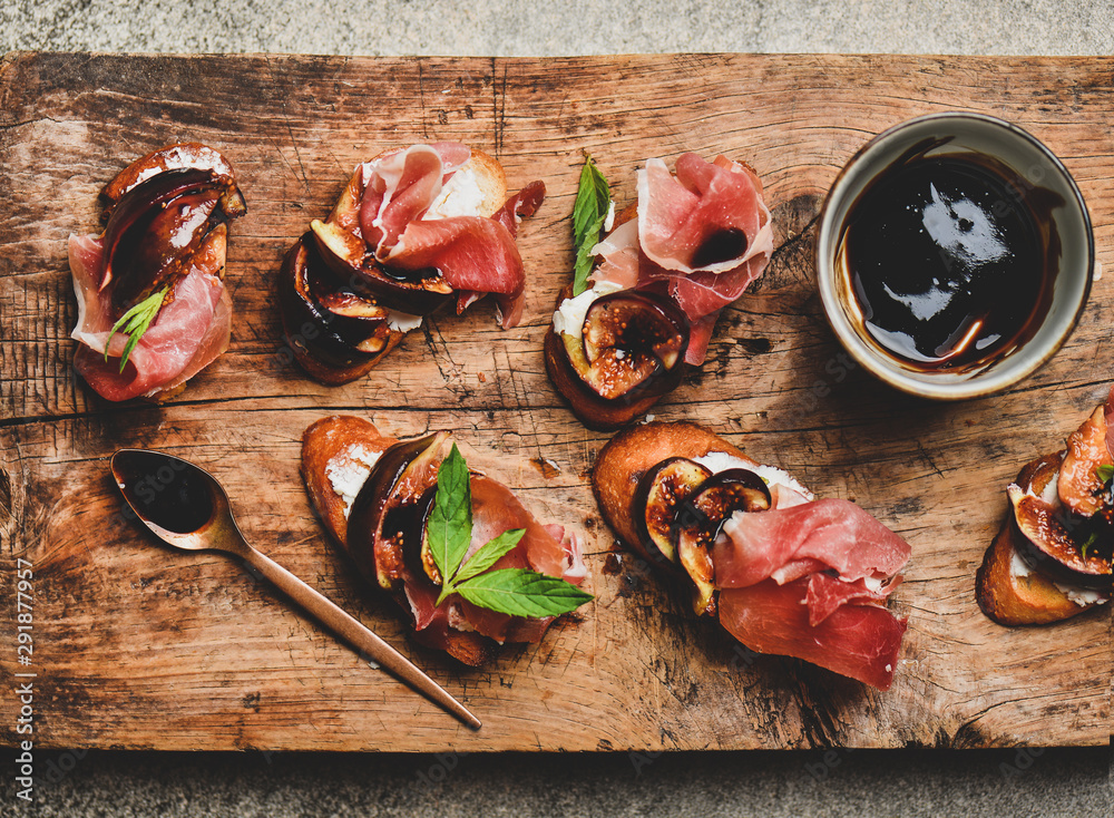 Party or catering food. Flat-lay of crostini with prosciutto, goat cheese and grilled figs on rustic
