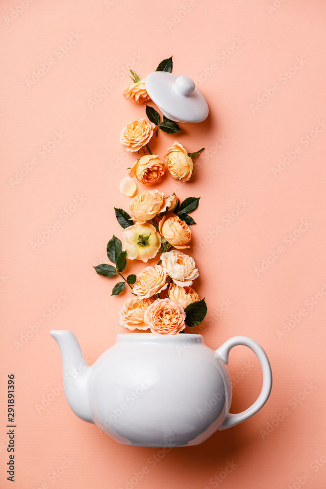 由粉色背景下的橙色玫瑰制成的whte茶壶的创意布局