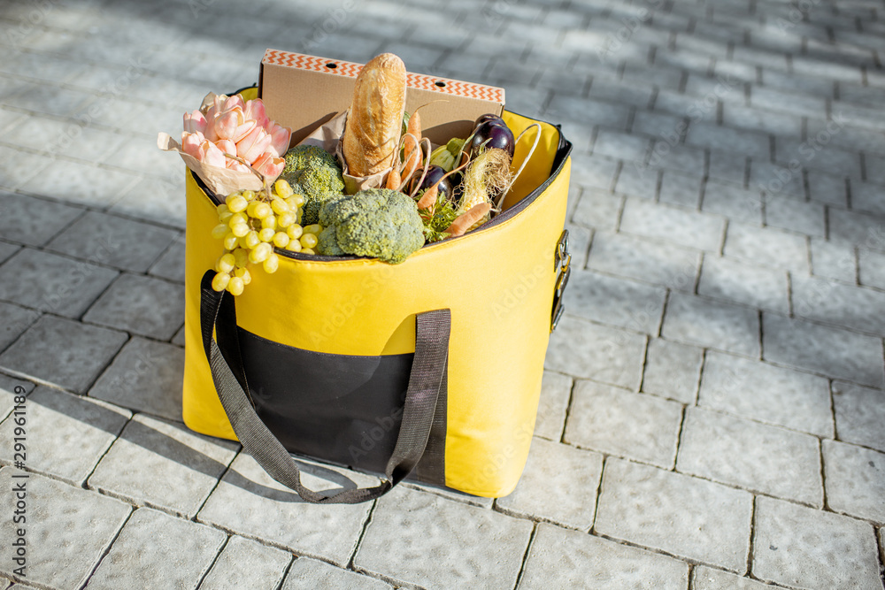 装满新鲜食物、鲜花和披萨盒的保温袋，在户外人行道上运送。新鲜