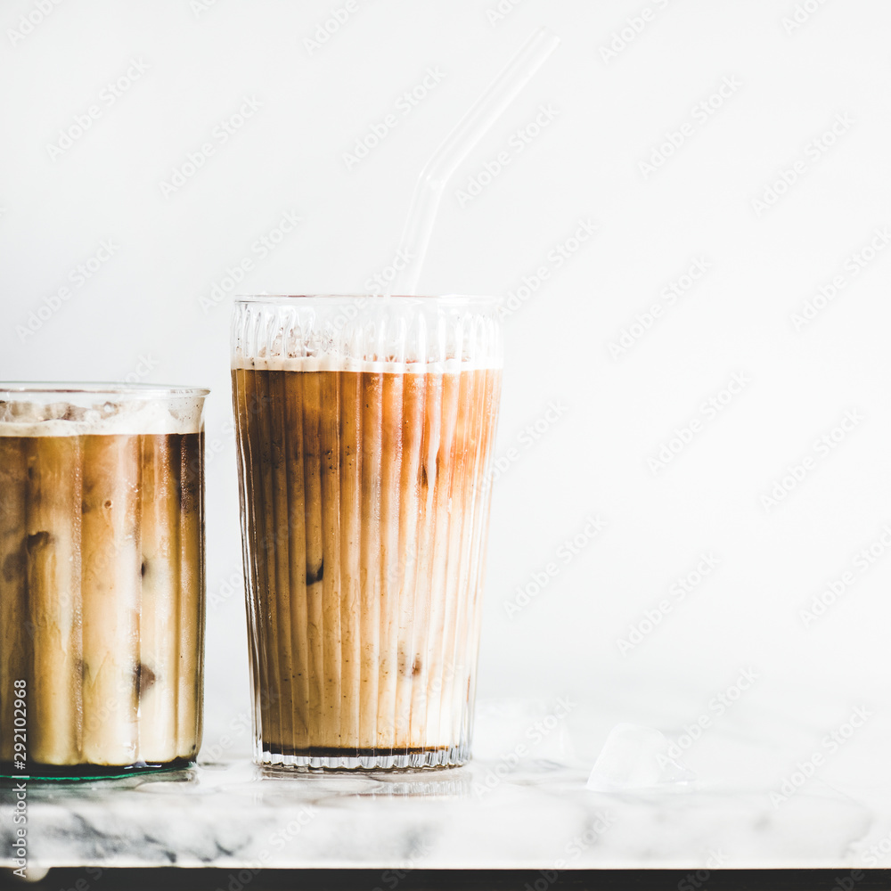 夏日清凉饮料概念。自制冰镇拿铁咖啡，装在玻璃杯里，吸管放在大理石上