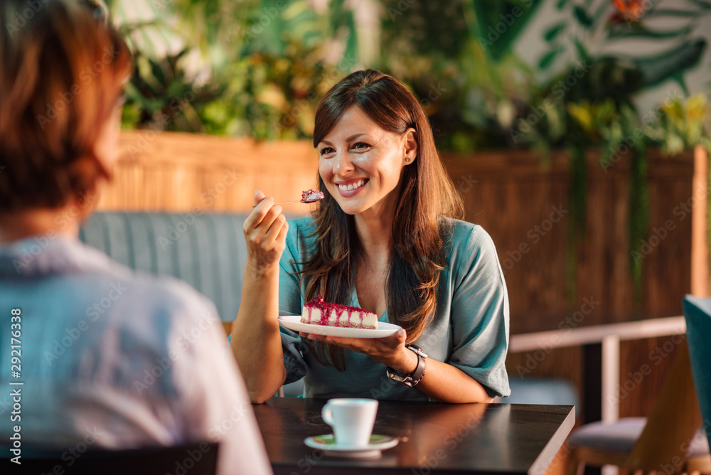 一个美丽乐观的女人的画像，在咖啡馆和朋友聊天，吃蛋糕。