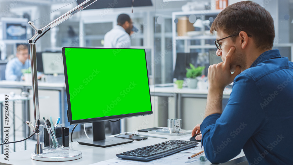 工程师在后台使用绿色实体屏幕台式电脑的超肩镜头