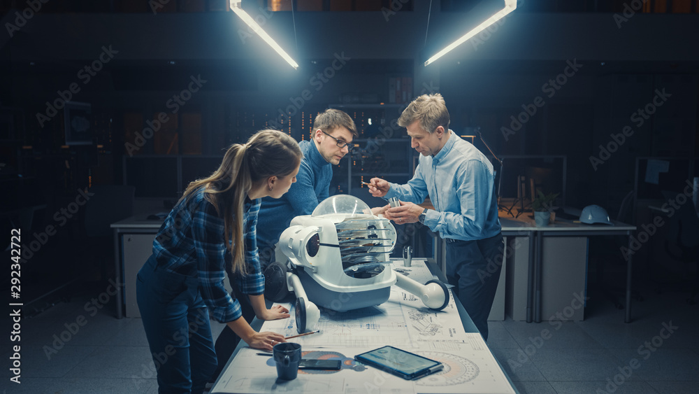 机器人工程设施深夜三位技术工程师在轮式上交谈和工作