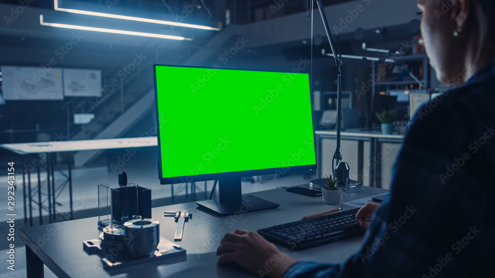 工程师在使用绿色实体屏幕台式电脑时的肩上镜头。工业设计