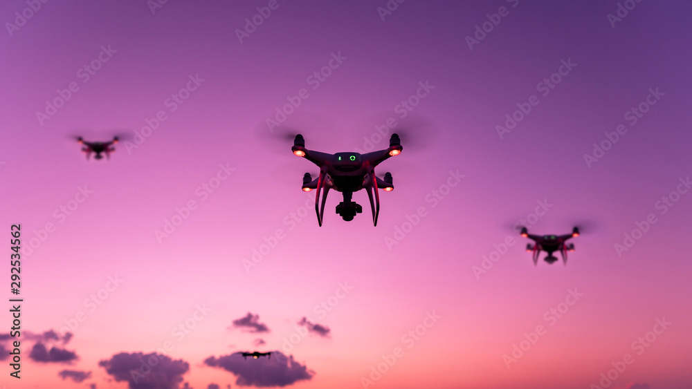 带数码相机的无人机四旋翼机在日落傍晚飞行美丽的自然光背景