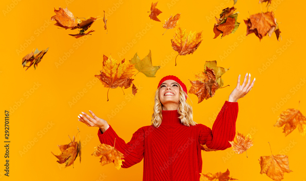 快乐、感性、开朗的女孩带着秋叶大笑，在彩色叶子上编织秋天的红色帽子