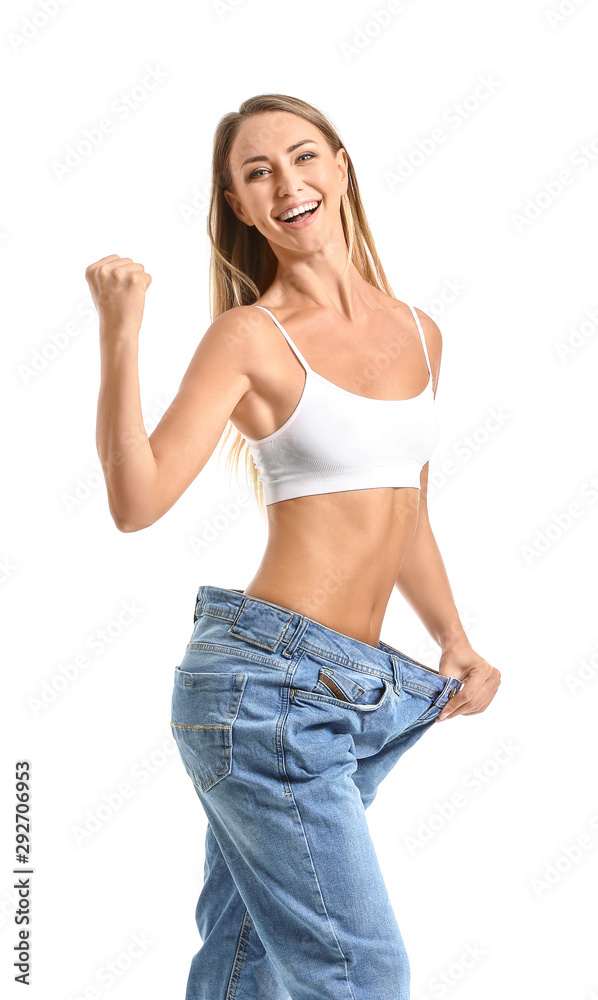快乐的年轻女人穿着白色背景的宽松牛仔裤。减肥概念