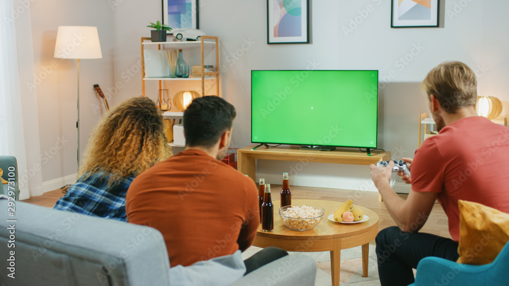 在客厅里，三个朋友在绿色Chroma键屏幕上竞争玩电子游戏，使用Co