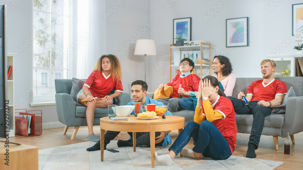 在家里，一群穿着队服的体育迷在电视上观看体育比赛，他们欢呼