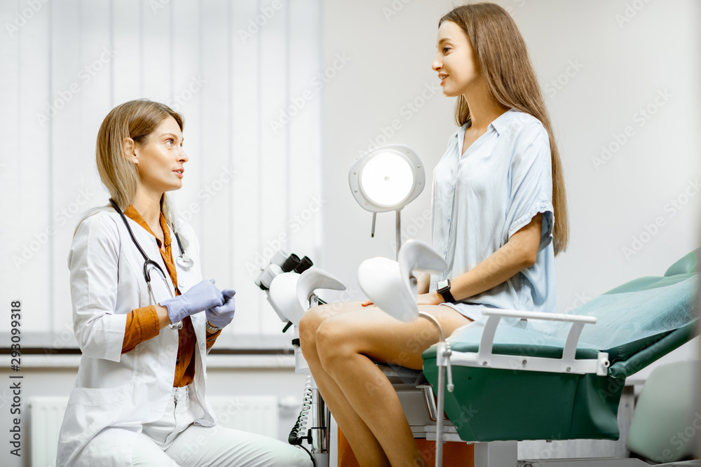 Gynecologist preparing for an examination procedure for a pregnant woman sitting on a gynecological 