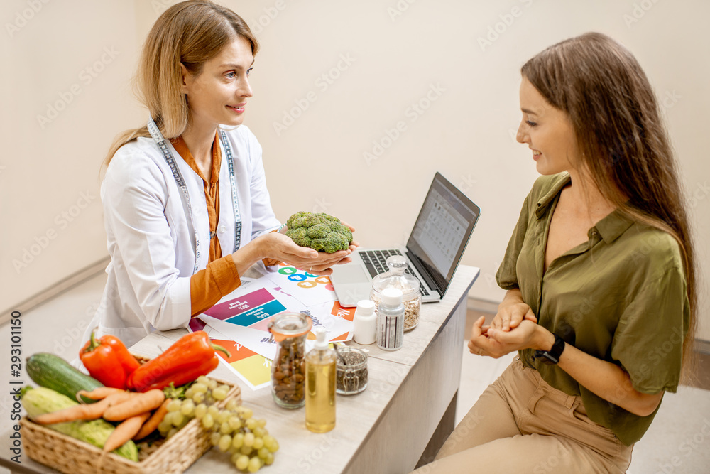 Nutritionist with young woman client talking about meal plan and healthy products during a medical c
