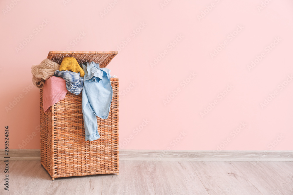 Basket with laundry on floor near color wall
