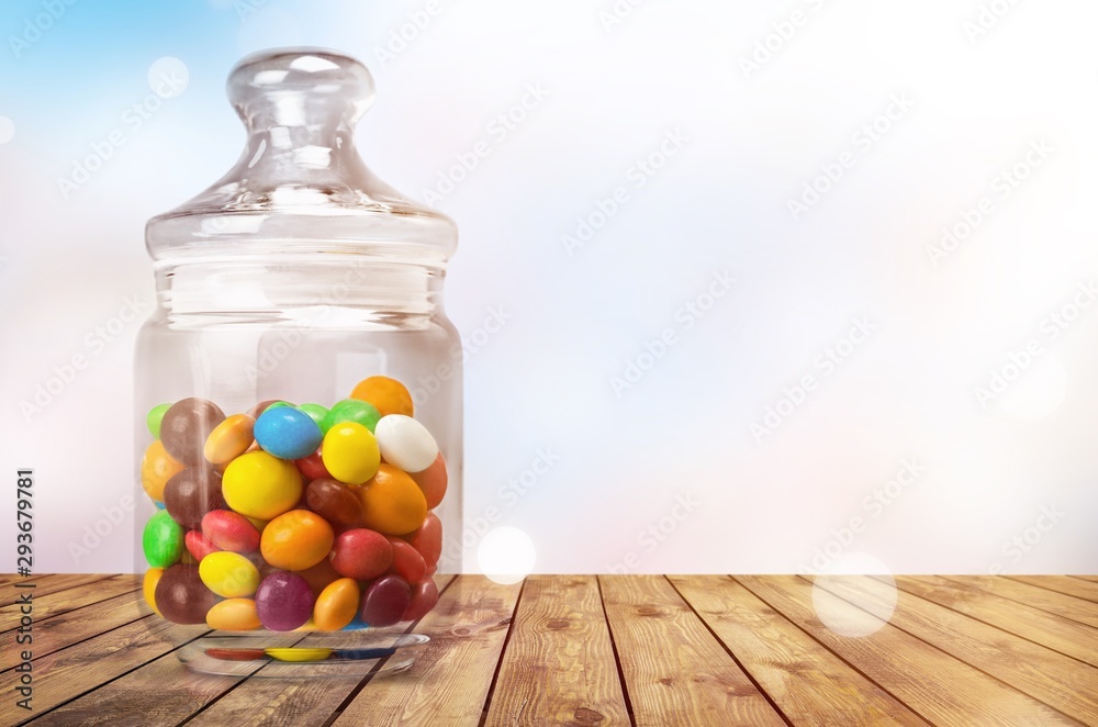 透明玻璃罐，桌上放着五颜六色的巧克力糖果