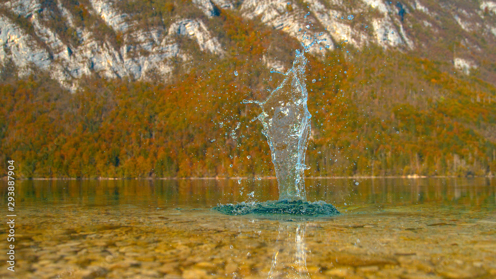 特写：一块石头掉进翡翠湖中并飞溅的风景镜头