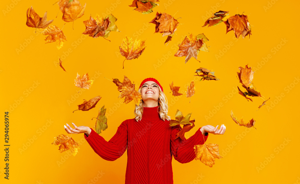 快乐、感性、开朗的女孩带着秋叶大笑，在彩色叶子上编织秋天的红色帽子