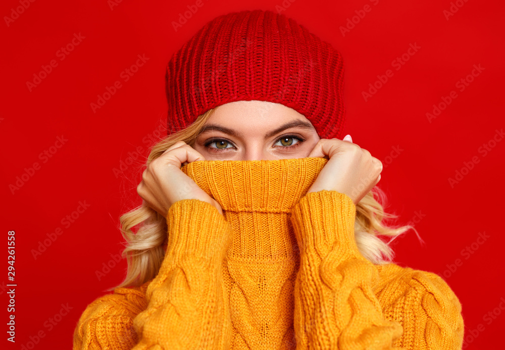 快乐、情绪化、开朗的女孩带着红色背景的针织秋帽大笑