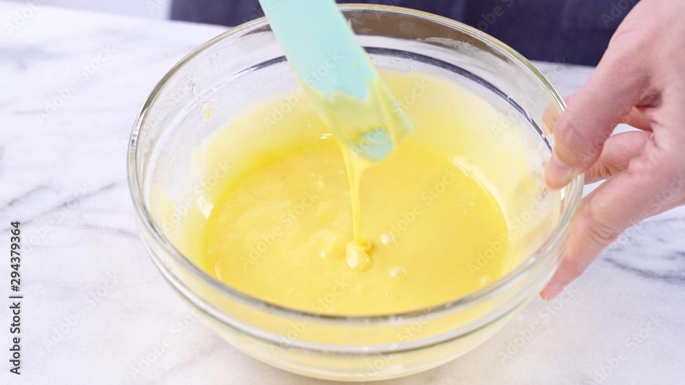 用绿色橡胶抹刀搅拌工具将蛋黄搅拌到蛋糕面糊中，搅拌至光滑起泡