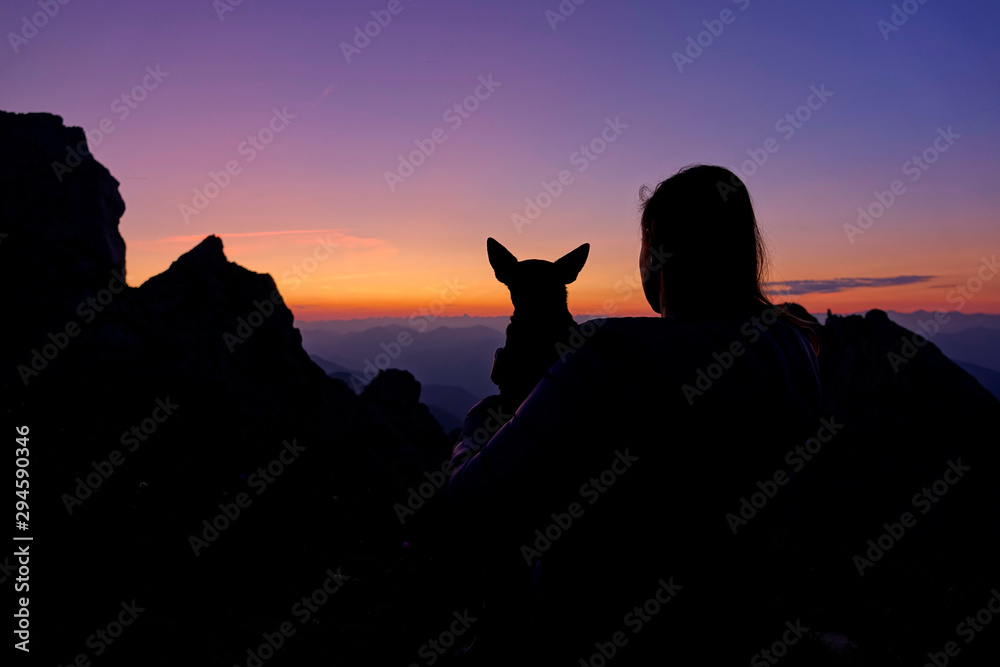 沉默：女孩和她的狗在朱利安阿尔卑斯山徒步旅行后观看日落