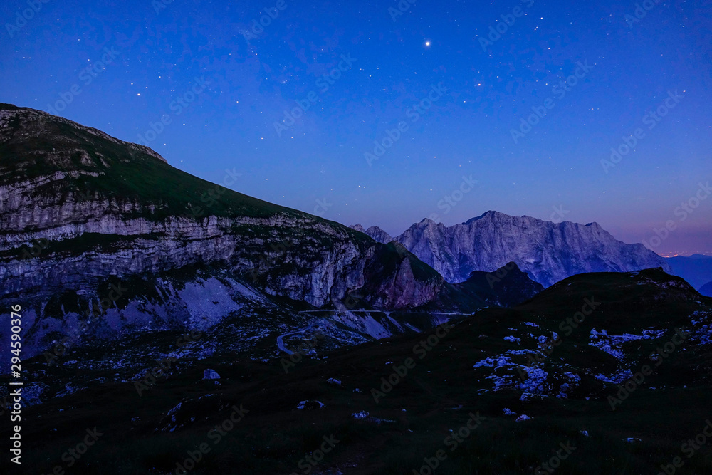 宁静的朱利安阿尔卑斯山上，晨曦中的星空覆盖着岩石山脉。