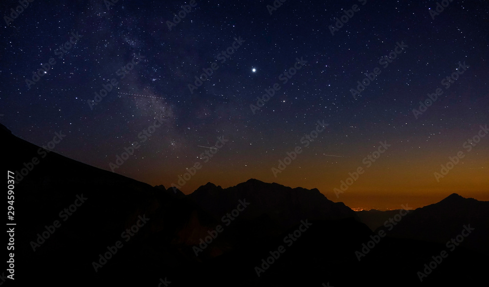Shooting stars fly across the evening sky spanning above the serene Julian Alps.