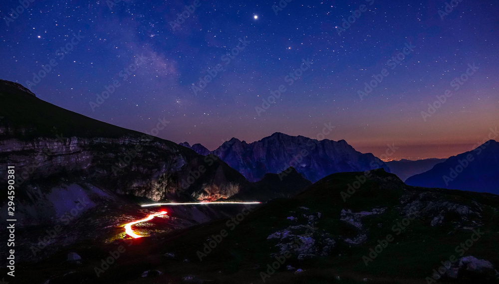 时光倒流：昏暗的车灯在星空下沿着山路行驶。