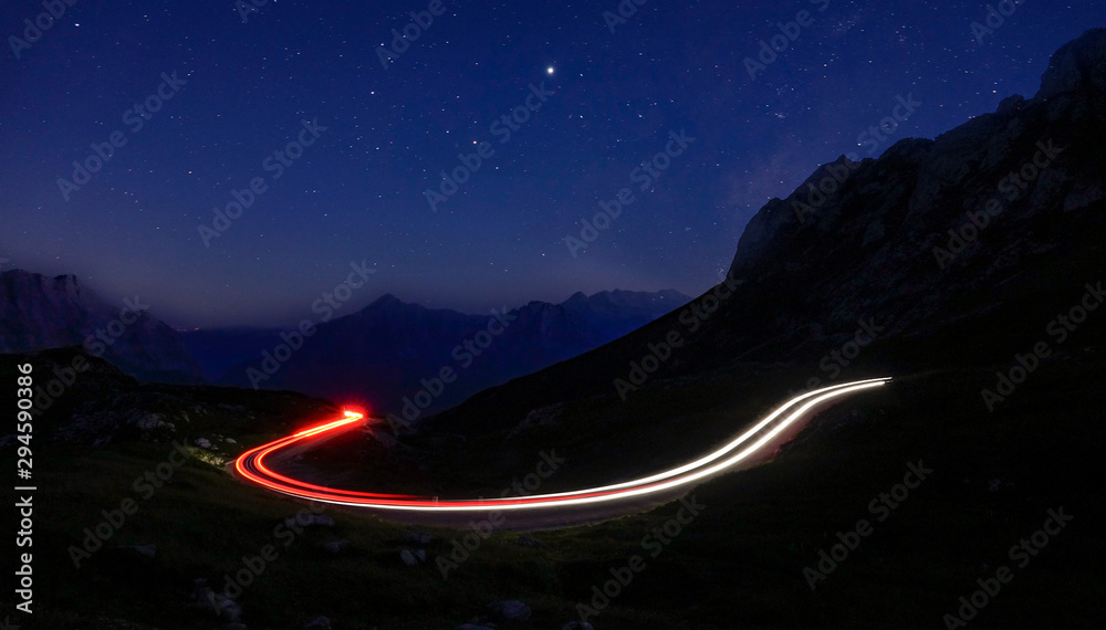 时光倒流：汽车灯光在夜间形成一条穿过山脉的模糊轨迹