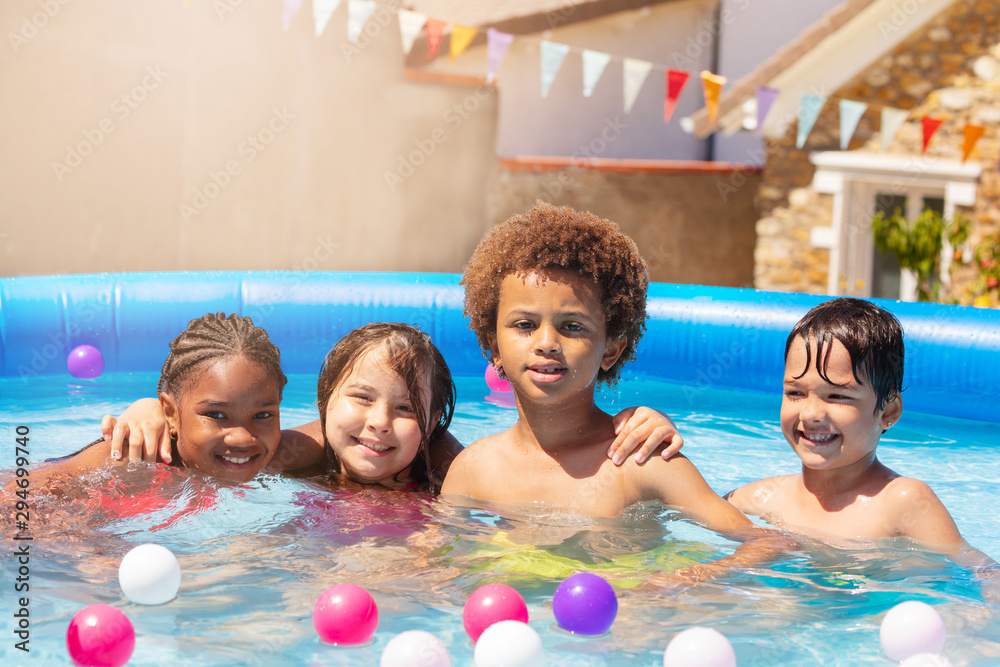 四个快乐的孩子在游泳池里拥抱坐着微笑