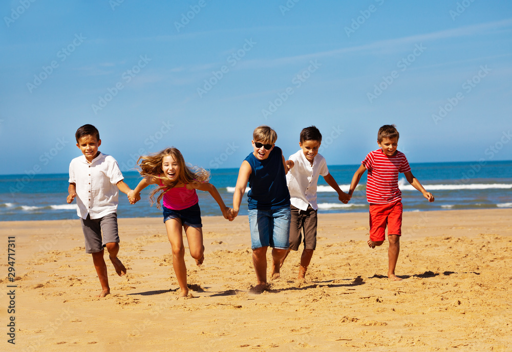 快乐快乐的孩子们在海滩上牵手奔跑