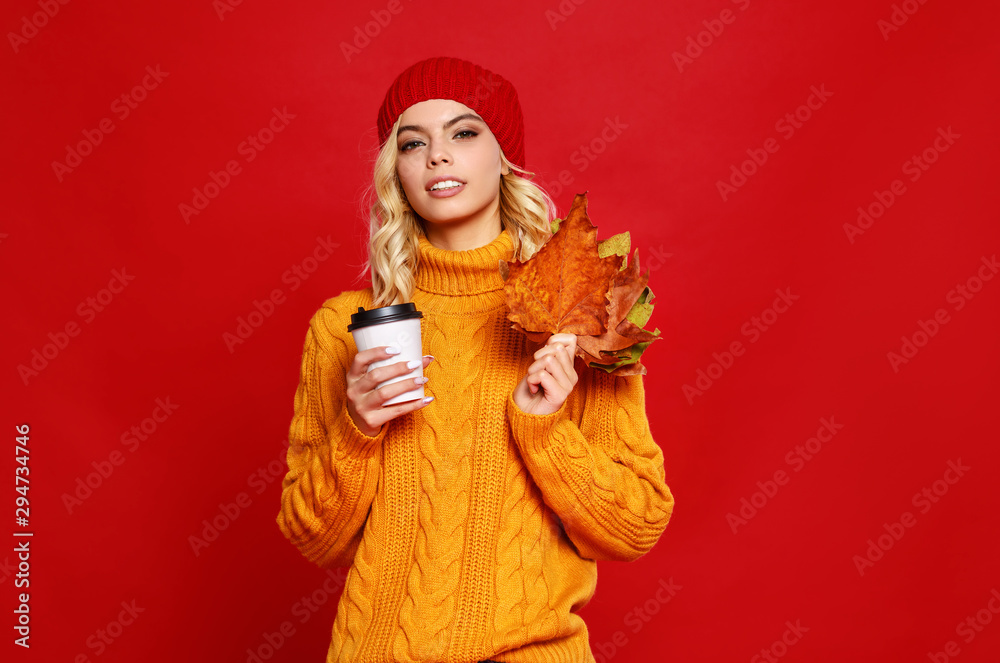 快乐、情绪化、开朗的女孩，戴着针织秋帽，在彩色红裤子上喝杯咖啡，开怀大笑