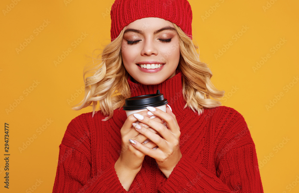 快乐、情绪化、开朗的女孩，戴着针织秋帽，在彩色红裤子上喝杯咖啡，开怀大笑