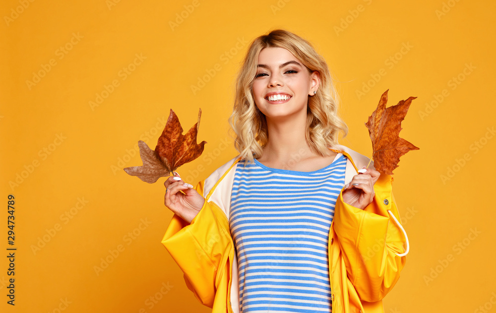 黄色背景上有秋叶的快乐感性女孩。