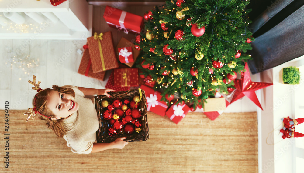 幸福的女人在家装饰圣诞树。