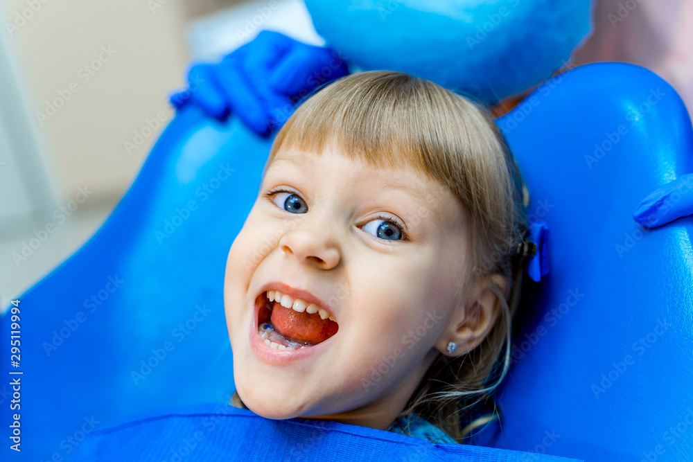 牙科诊所里的可爱女孩。口腔柜里的孩子张着嘴。快乐的情绪。