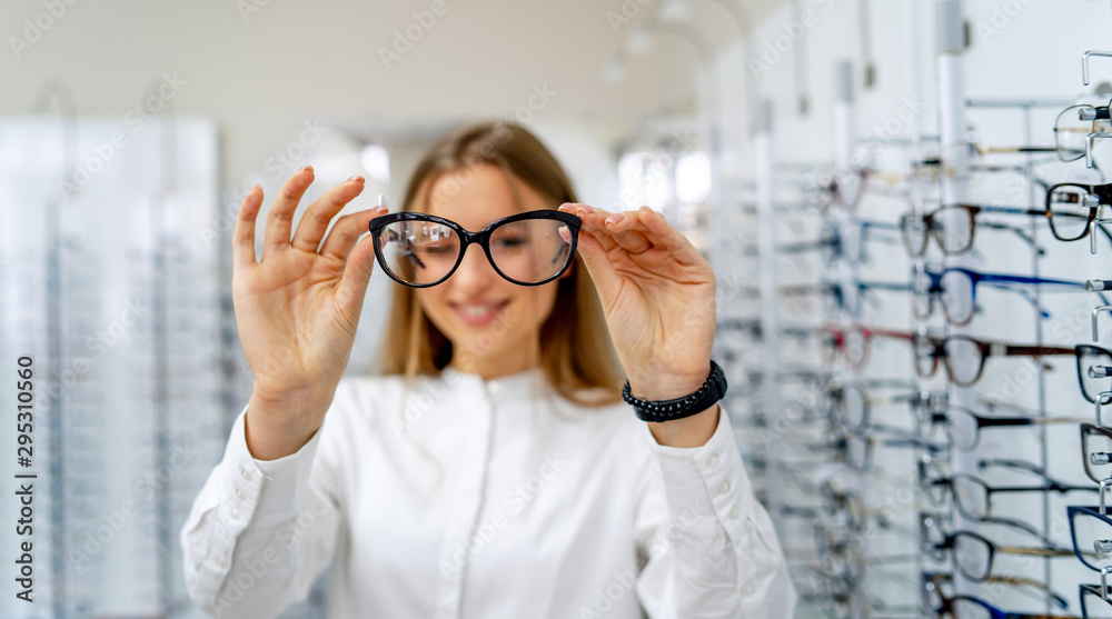 快乐的女验光师，眼镜师站在眼镜店的后台，配着一副眼镜。哇