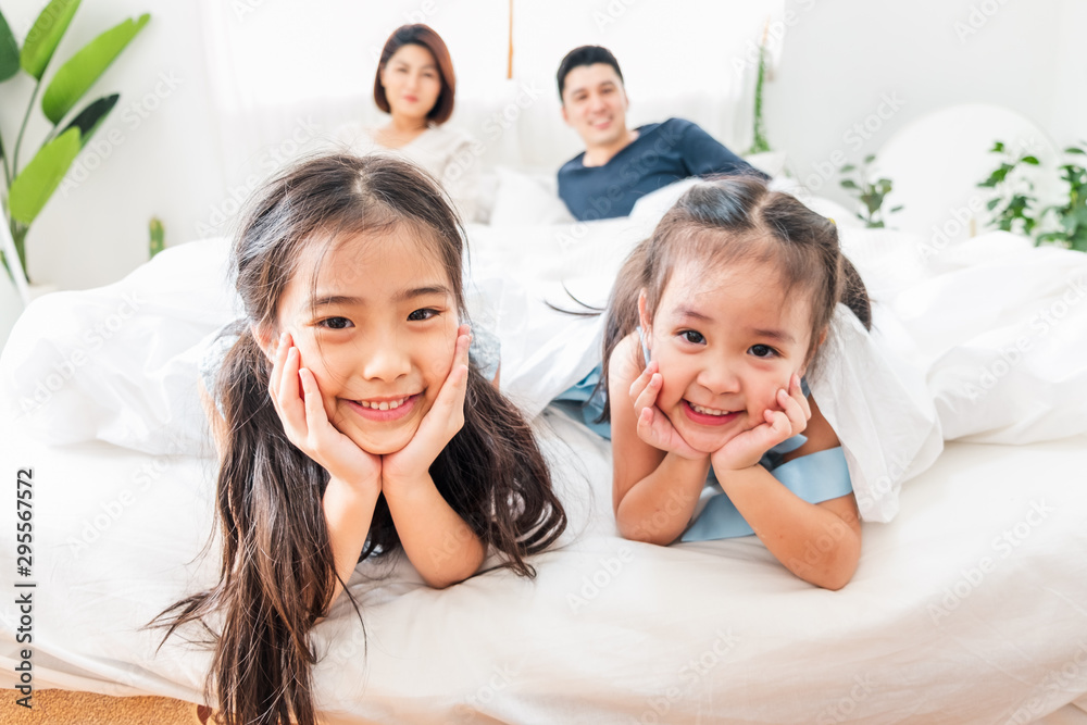 快乐的亚洲家庭躺在卧室的床上，面带微笑