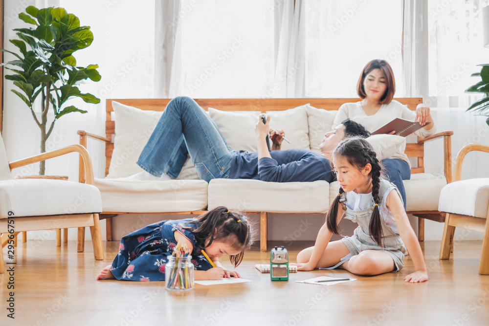 亚洲家庭带着可爱的女儿在家里的客厅里画画