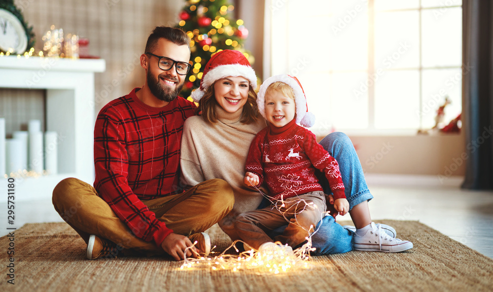 幸福的家庭装饰圣诞树，父母带着花环和儿子玩耍。