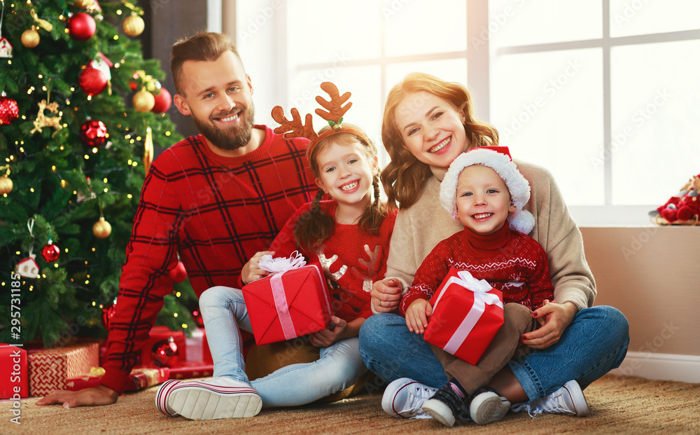 家里圣诞树旁有礼物的幸福家庭。