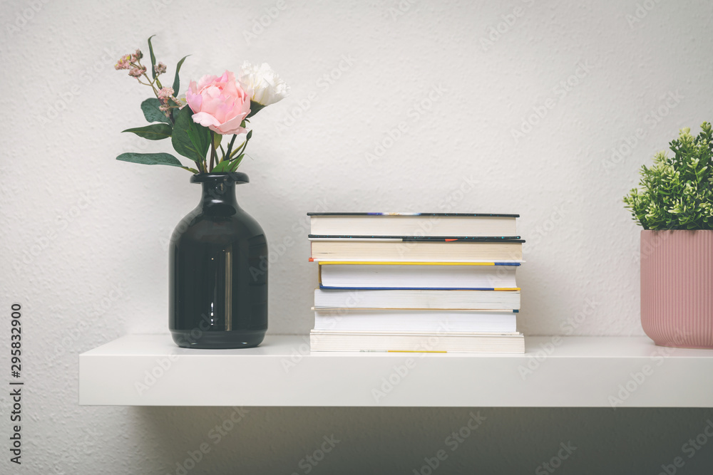 白墙上的架子，上面有书和花盆