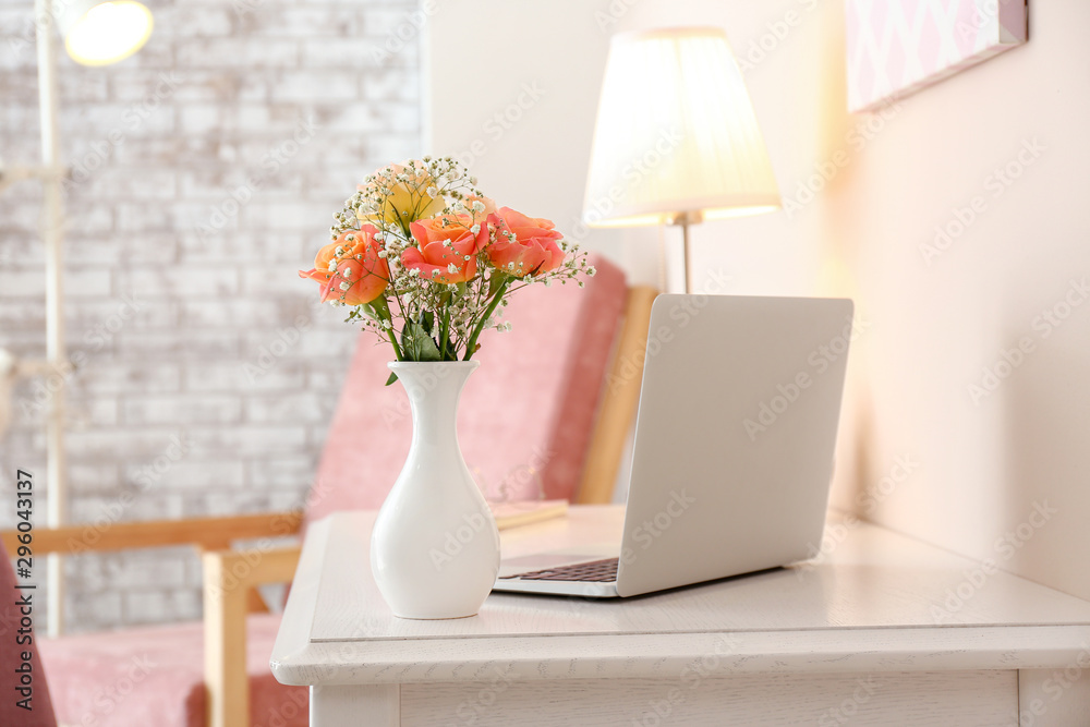 房间里花瓶里的漂亮花束和桌子上的笔记本电脑