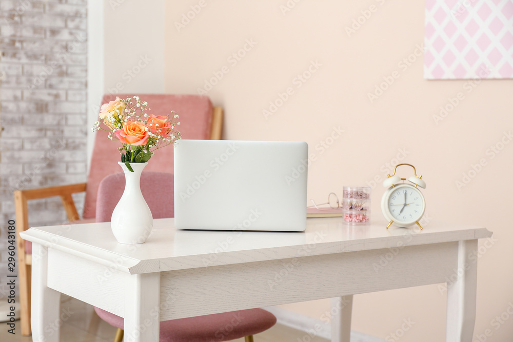 房间里花瓶里的漂亮花束和桌子上的笔记本电脑