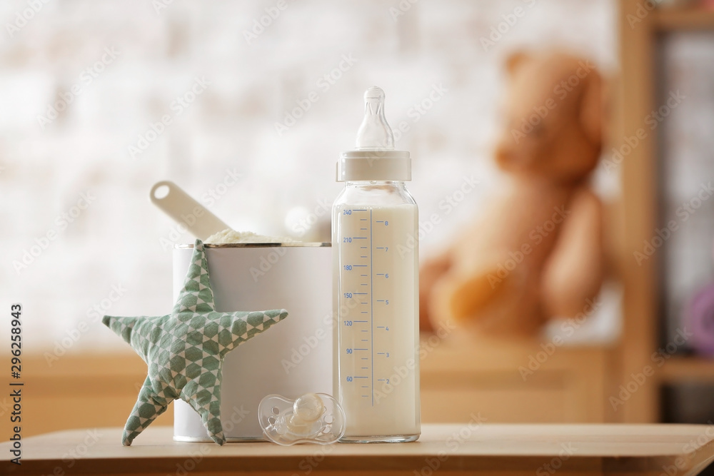 房间桌子上放着一瓶牛奶和一罐婴儿配方奶粉