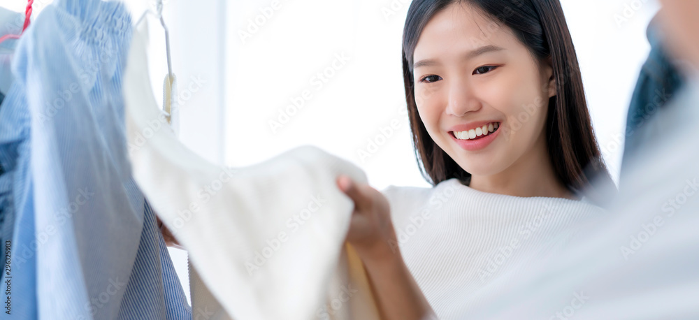 漂亮幸福的亚洲女人在商店白色房间背景下穿着有趣的衣服购物