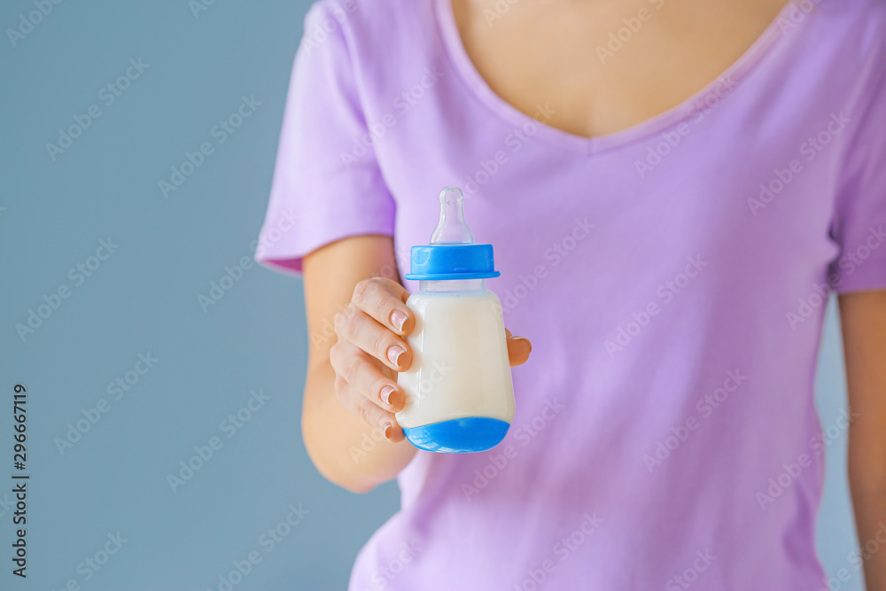 母亲拿着一瓶彩色背景的婴儿配方奶粉，特写