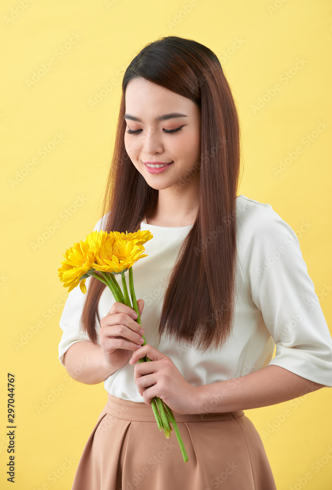 幸福的年轻女子手里拿着一束黄色背景的鲜花