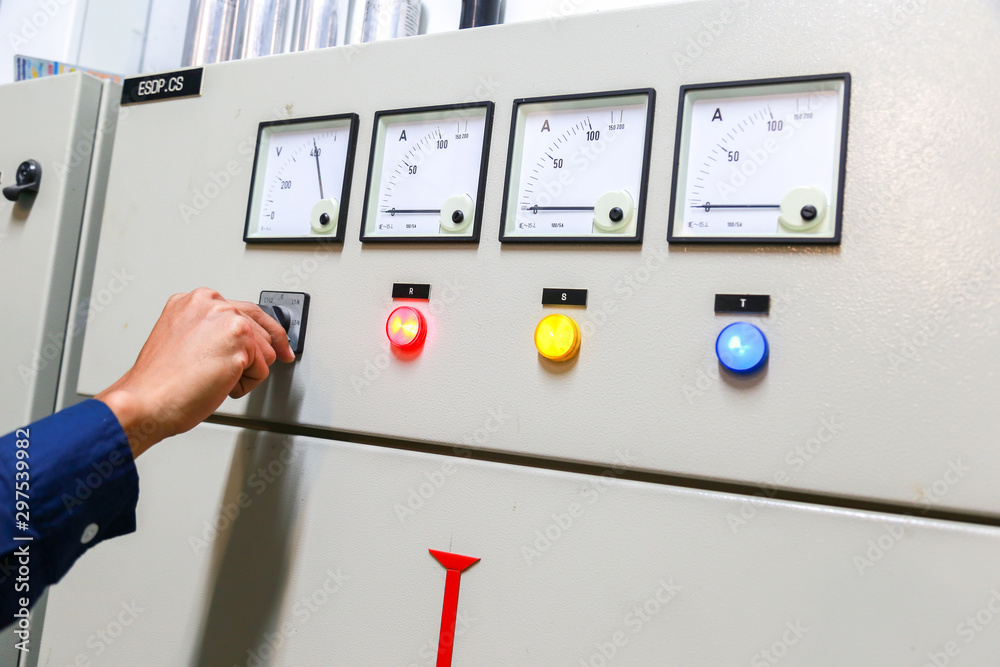 工业技术人员检查发电厂控制面板中的电压或电流状态。