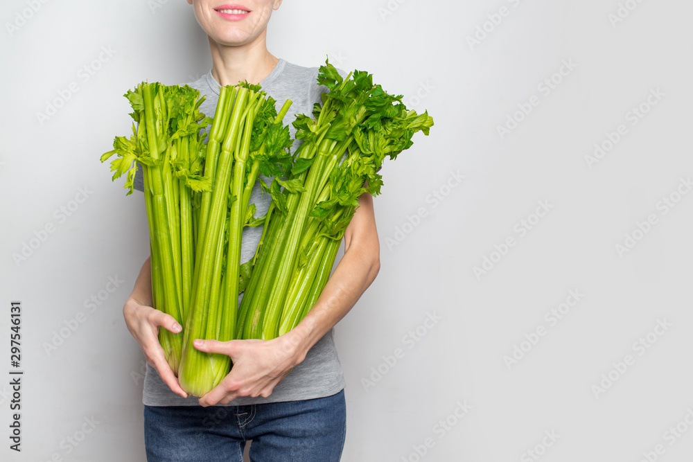 妇女手持绿色新鲜芹菜。健康饮食、素食、节食和以人为本